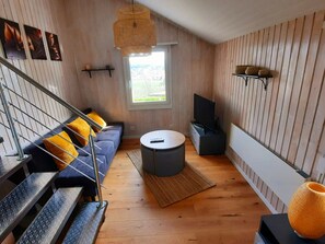 Un salon moderne avec un canapé, une table basse ronde, un téléviseur et un escalier.