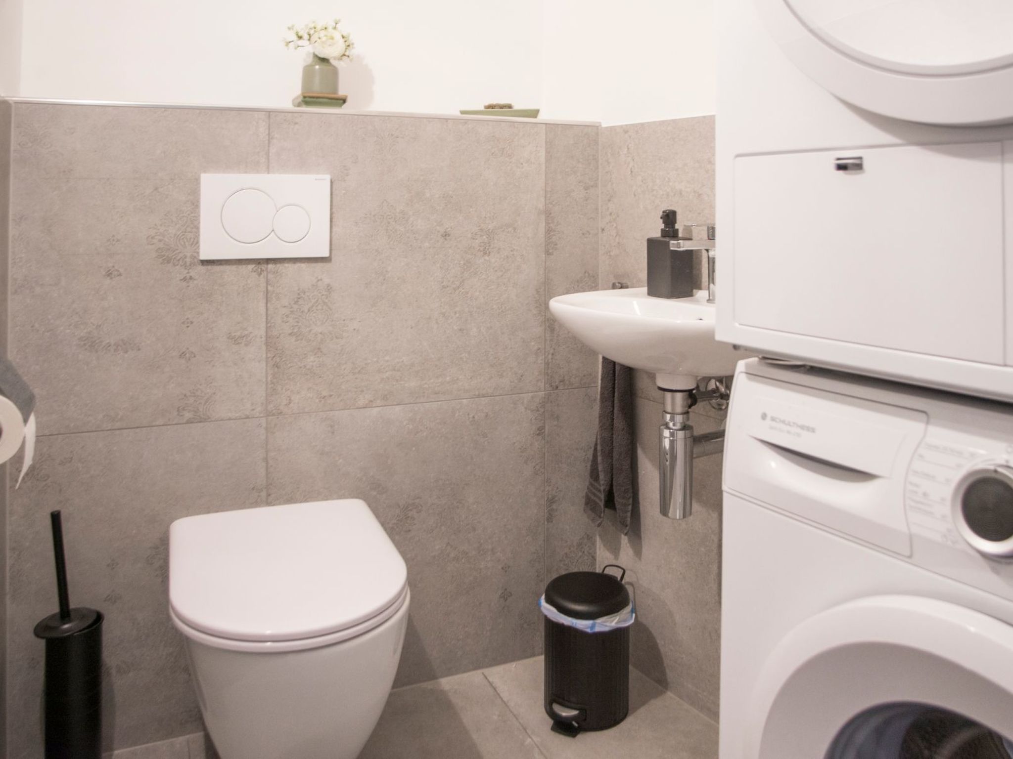 Ein kleines Badezimmer mit Toilette, Waschbecken und Waschmaschine.