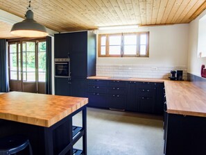 A modern kitchen with dark cabinets, a wooden countertop, and a large window. - Appartement - Gîte chez MarEdo, (Montmelon), by Interhome (Montmelon-St.Ursanne)