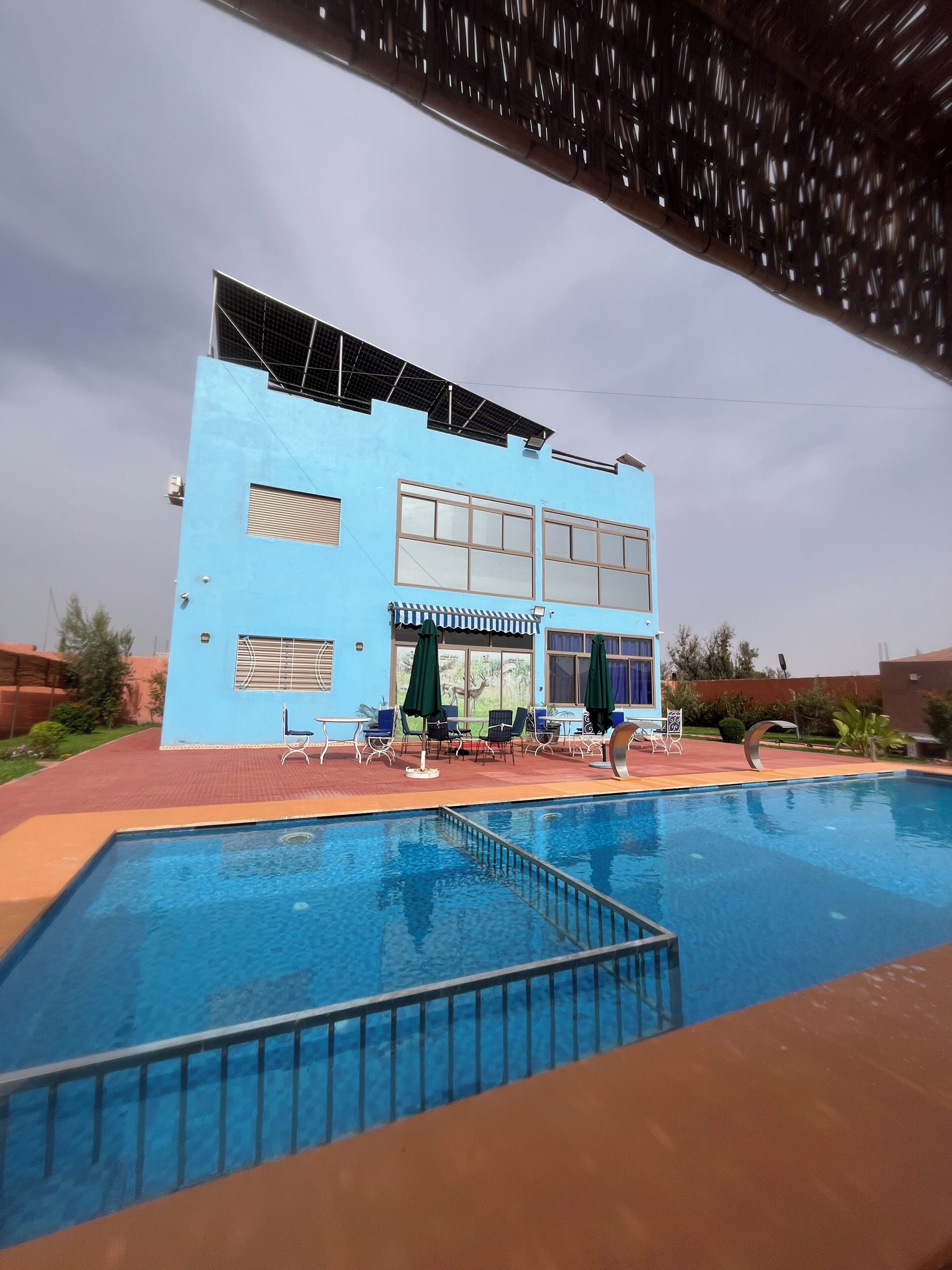 A two-story building with a swimming pool, outdoor seating, and a covered area.
