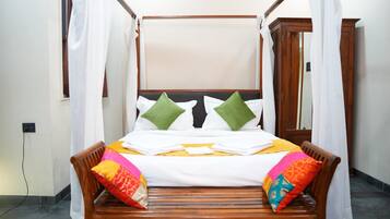 A four-poster bed with white linens and green pillows, a wooden headboard, and a yellow bedspread.