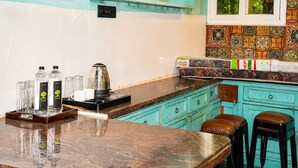 Una cocina con encimera de madera, cafetera y copas de vino colgadas.