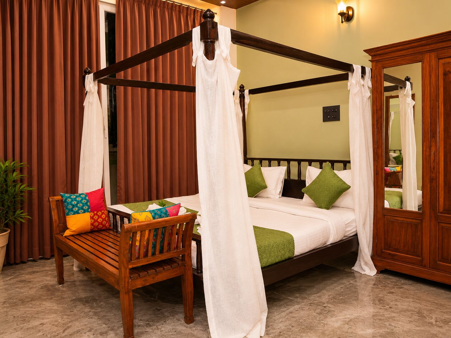 A four-poster bed with a canopy, a wooden chair with colorful cushions, and a potted plant.
