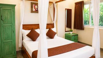 A four-poster bed with white and brown bedding, a green wardrobe, a small bedside table with a plant, and a window with curtains.