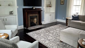 A living room with a fireplace, a television, and a sofa. - The Claxton house a Greenup county Historic home built in 1864 with hot tub (Greenup)