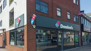 Domino's Pizza -ravintola, jossa on suuri lasinen etuikkuna, selkeästi näkyvä kyltti ja tiiliverhous.