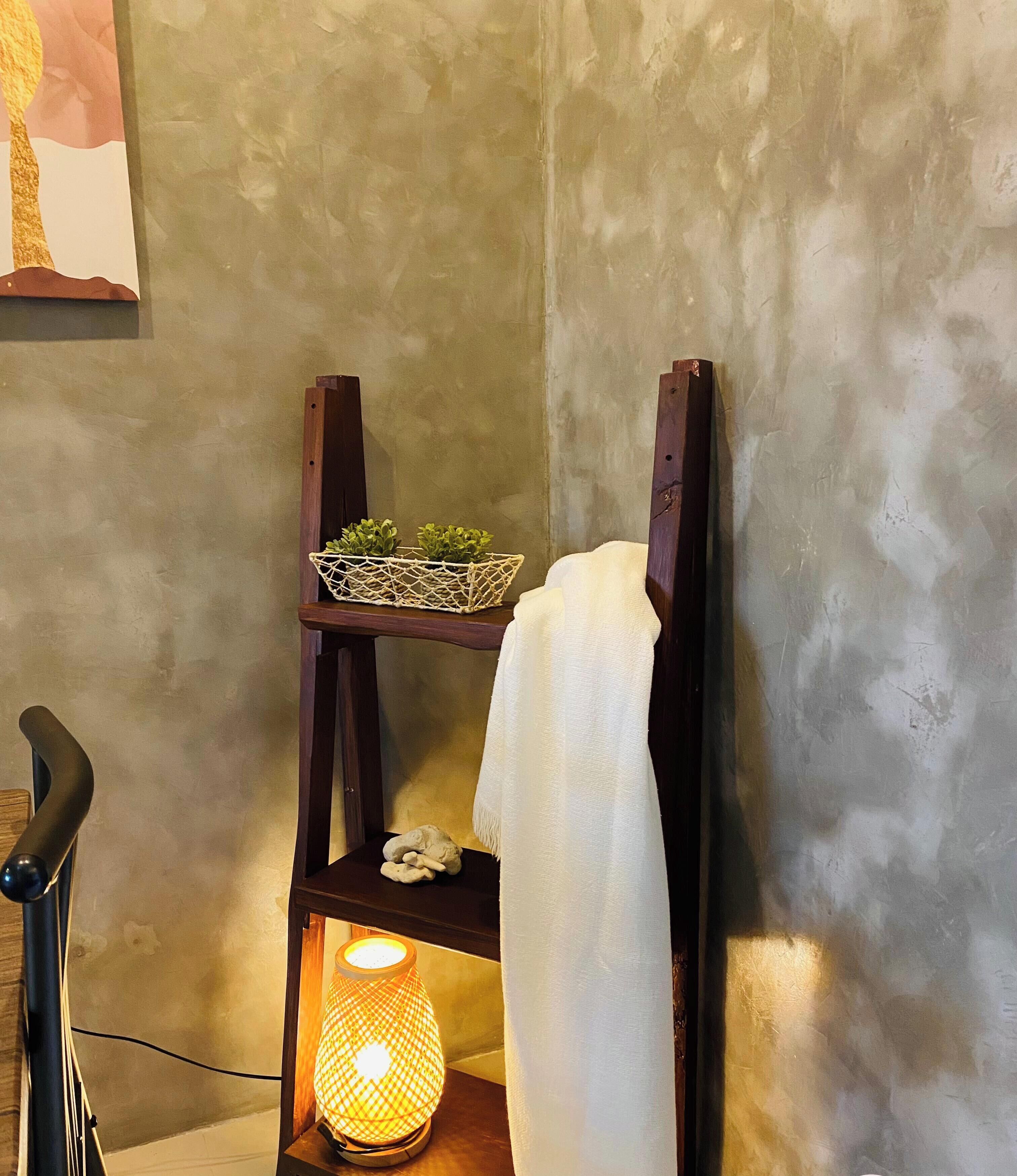 A corner of a room with a wooden shelf holding a small plant and a lamp.