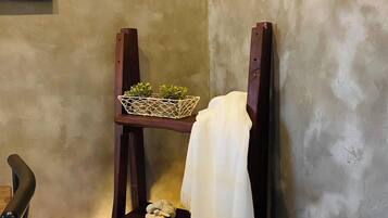A corner of a room with a wooden shelf holding a small plant and a lamp.