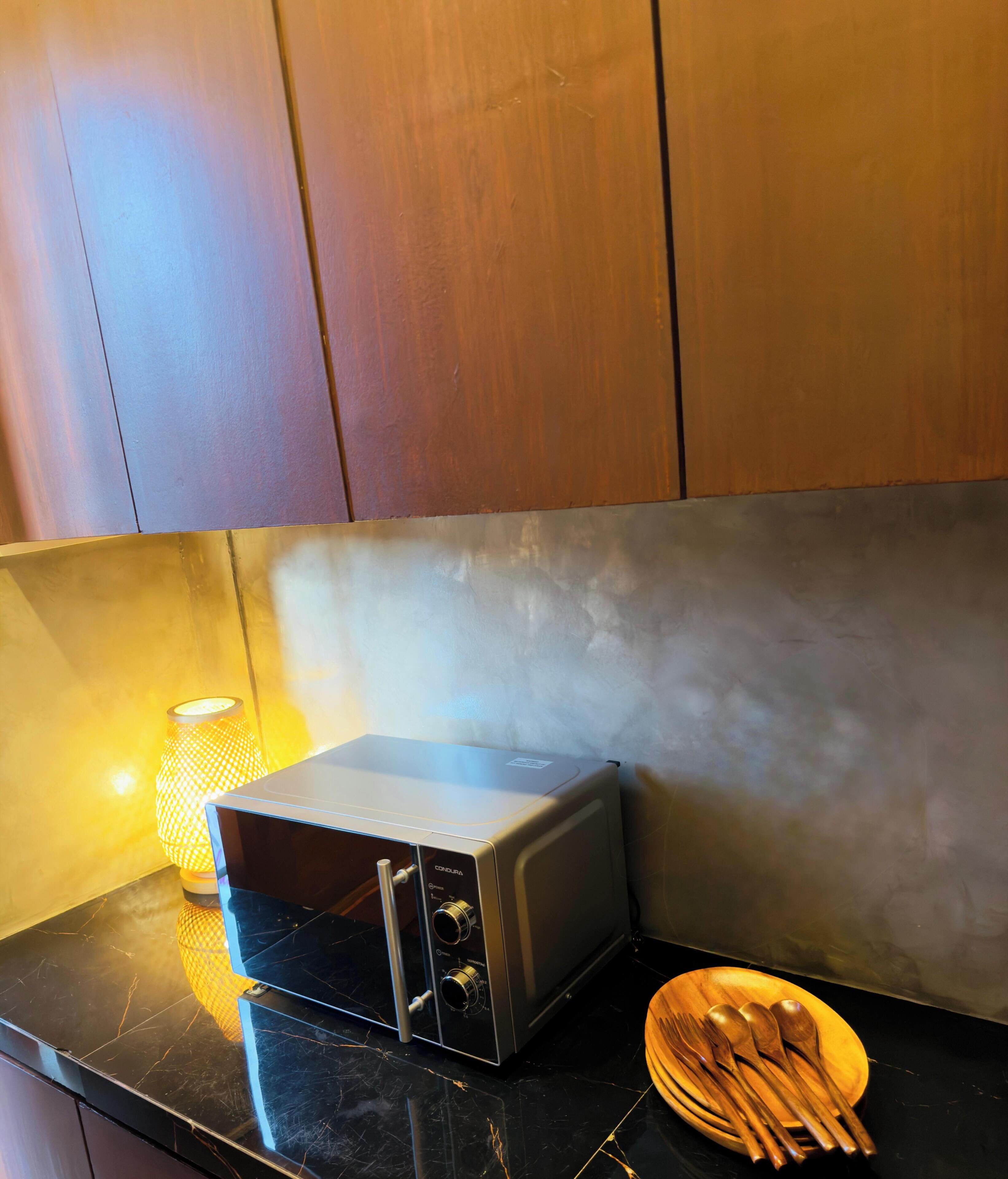 Eine Küche mit Toaster, einem Holzlöffel-Set und einer brennenden Kerze auf einer schwarzen Arbeitsplatte.