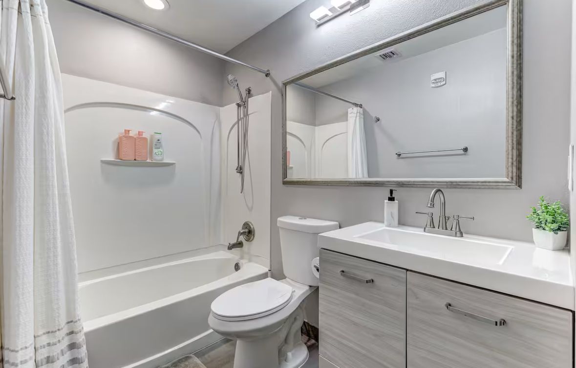 Un bagno moderno con vasca, WC, lavabo e uno specchio grande.