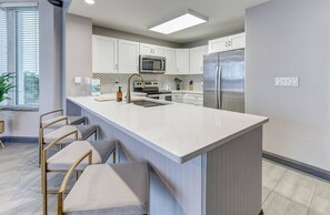 A modern kitchen with a central island, stainless steel appliances, and a window with blinds. - Spacious 2-bedroom condo with Lakeview in superb Orlando location Close 2 Disney (Orlando)