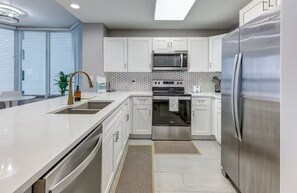 Eine moderne Küche mit weißen Schränken, Edelstahlgeräten und einem großen Kühlschrank.