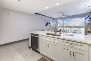 A modern kitchen with white cabinetry, a dishwasher, and a large window offering a view of the outdoors. - Spacious 2-bedroom condo with Lakeview in superb Orlando location Close 2 Disney (Orlando)
