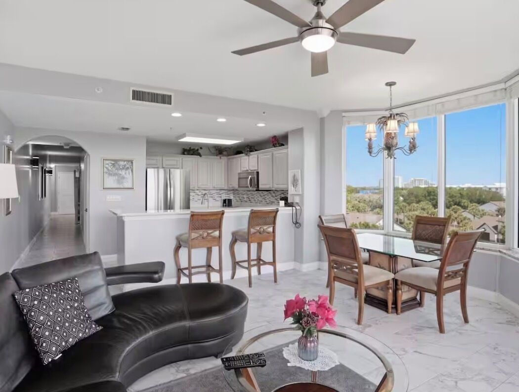 A modern living room with a sofa, a coffee table, and a dining area with chairs and a table.
