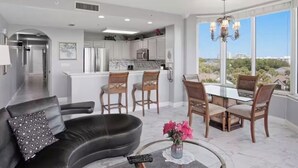 Uma sala de estar moderna com um sofá, uma mesa de centro e um espaço de jantar com cadeiras e uma mesa.