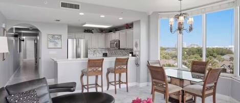 A modern living room with a sofa, a coffee table, and a dining area with chairs and a table.