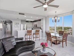 A modern living room with a sofa, a coffee table, and a dining area with chairs and a table. - 2-bedroom condo with Disney Fireworks view and Heated pools! (Orlando)