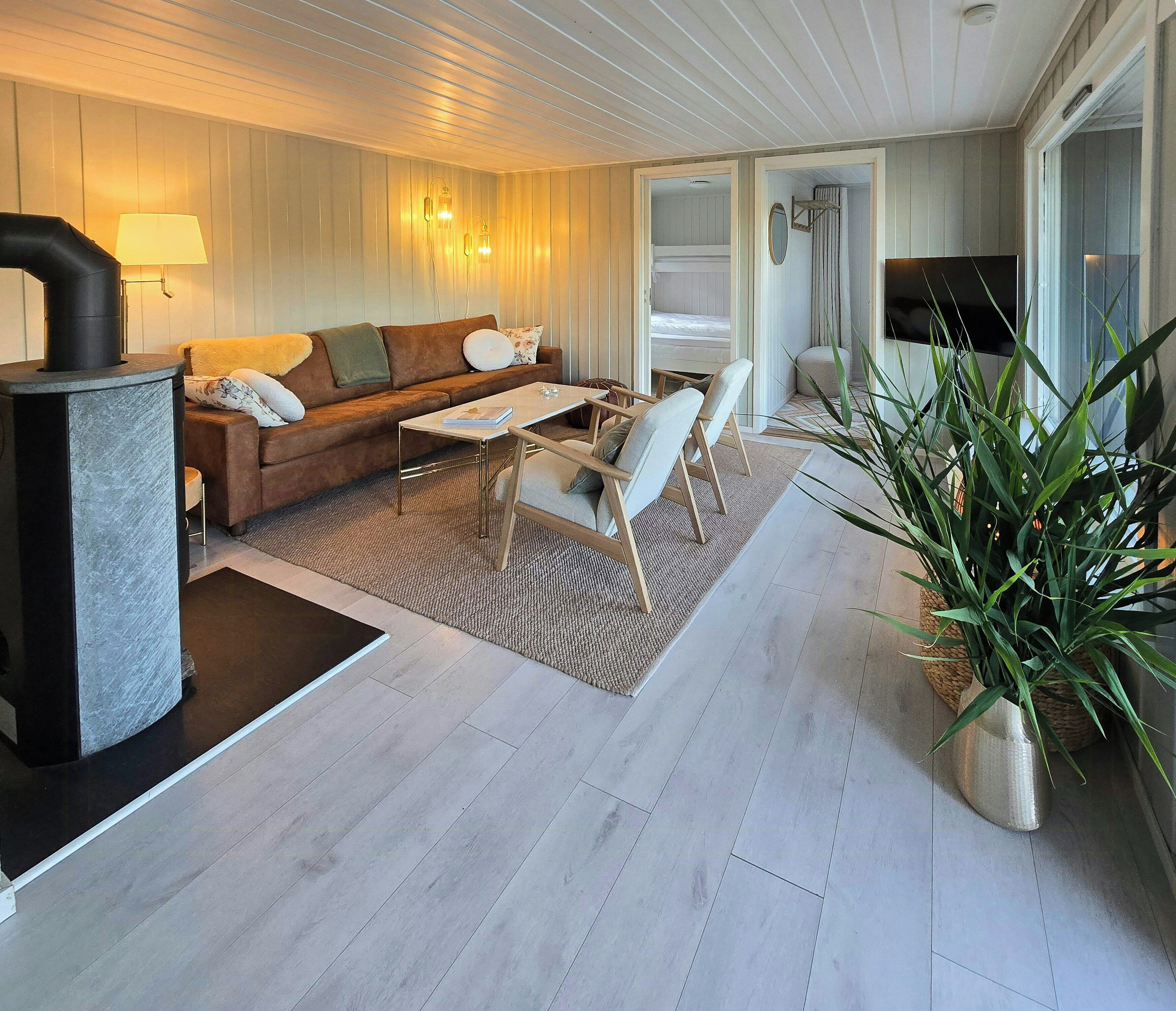 Een knusse woonkamer met een bank, salontafel en stoelen, een open haard en een televisie.
