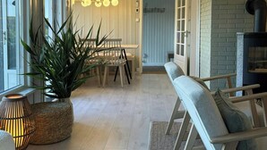 A spacious living area with a wooden bench, a dining table with chairs, a potted plant, and a fireplace. - Cabin with views over Hvaler archipelago (Gamle Frederikstad)