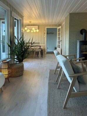A spacious living area with a wooden bench, a dining table with chairs, a potted plant, and a fireplace. - Cabin with views over Hvaler archipelago (Gamle Frederikstad)