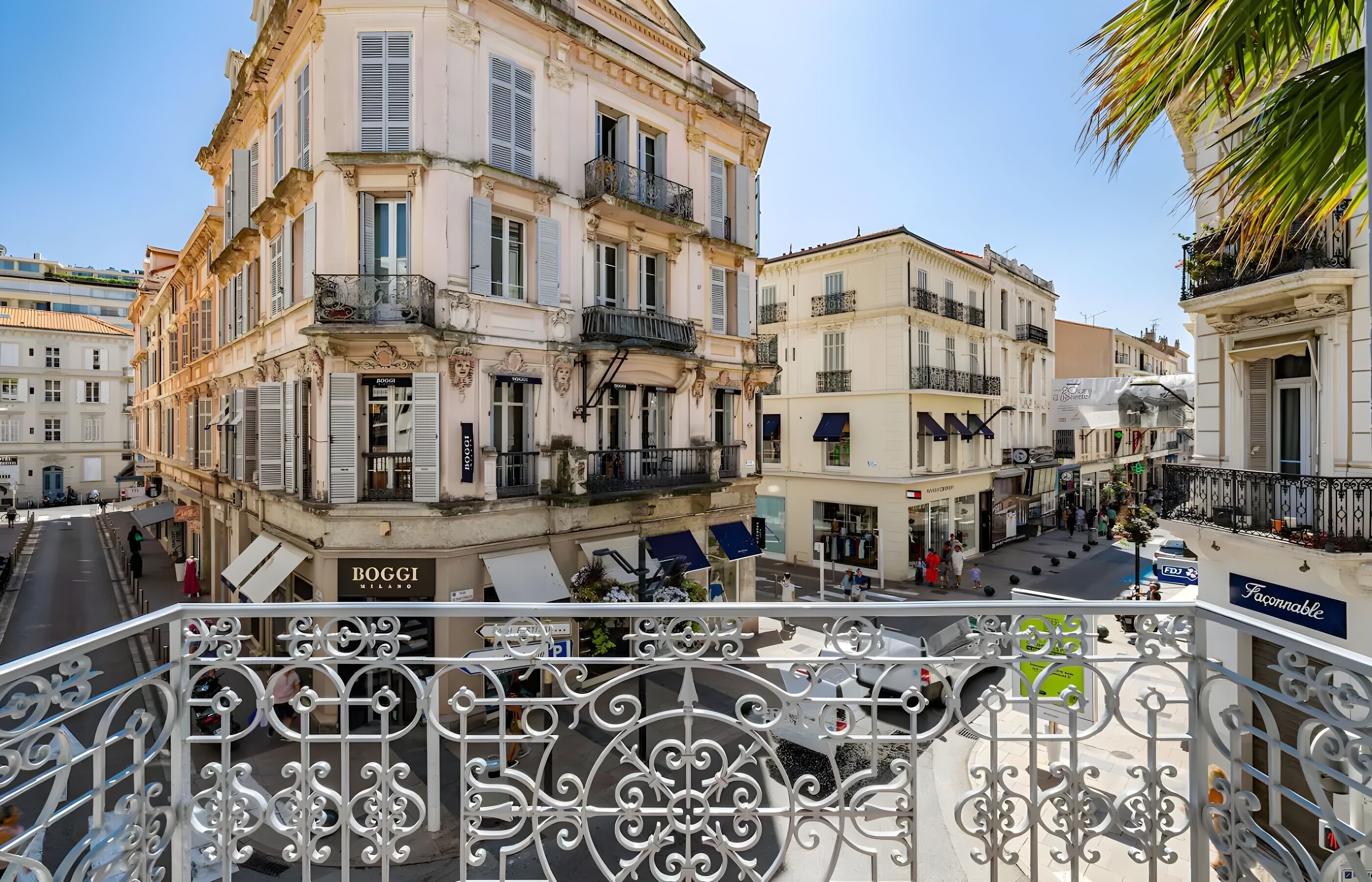 A street view with buildings, balconies, and a sign for 'BOGGI'.