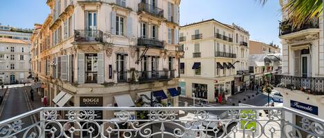 A street view with buildings, balconies, and a sign for 'BOGGI'.