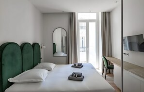 Een moderne hotelkamer met een groot bed, een bureau, een televisie en uitzicht op de stad.