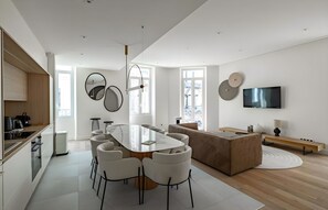 Eine moderne Küche mit Essbereich, einem an der Wand befestigten Fernseher und einem großen Fenster.