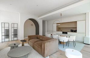 Un saló modern amb un sofà, una taula de centre i una zona de menjador amb cadires.