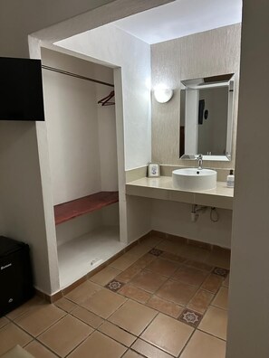Un baño con lavamanos blanco, un espejo y un perchero para toallas.