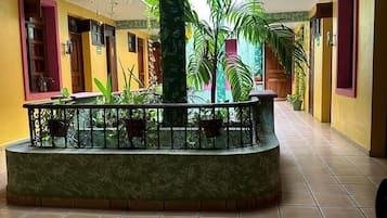 A spacious indoor area with a central column, tiled flooring, and potted plants.