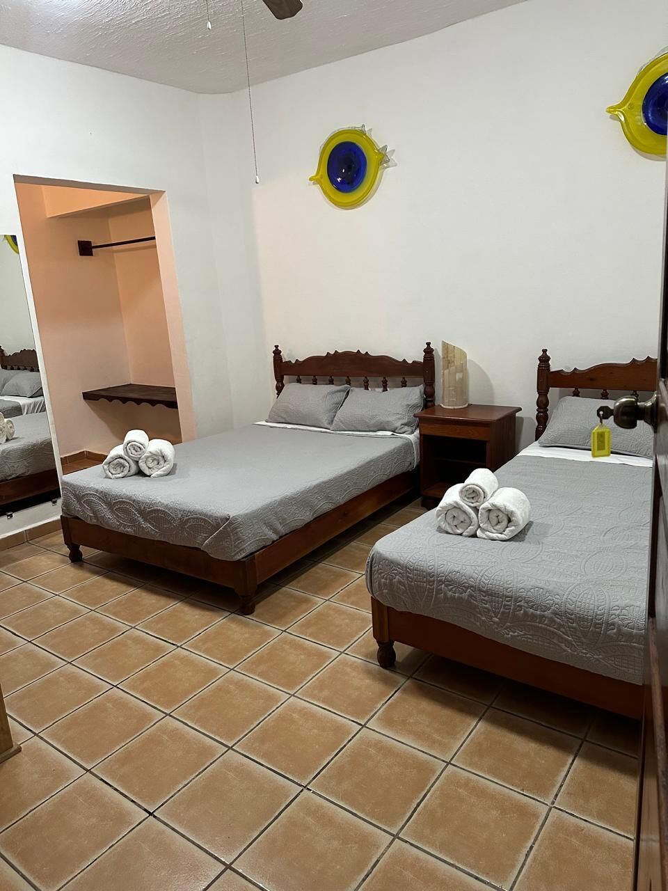 A hotel room with two beds, a wooden headboard, a nightstand, and a mirror.