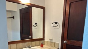 Un baño con lavamanos, espejo y puerta.