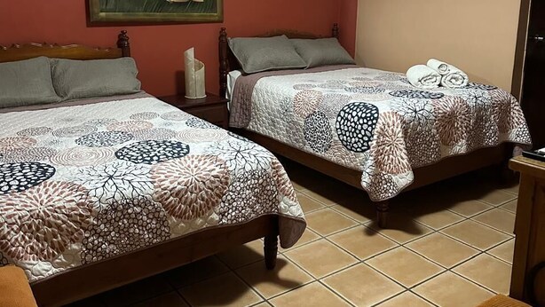 Un dormitorio con dos camas, un cuadro en la pared y una silla.