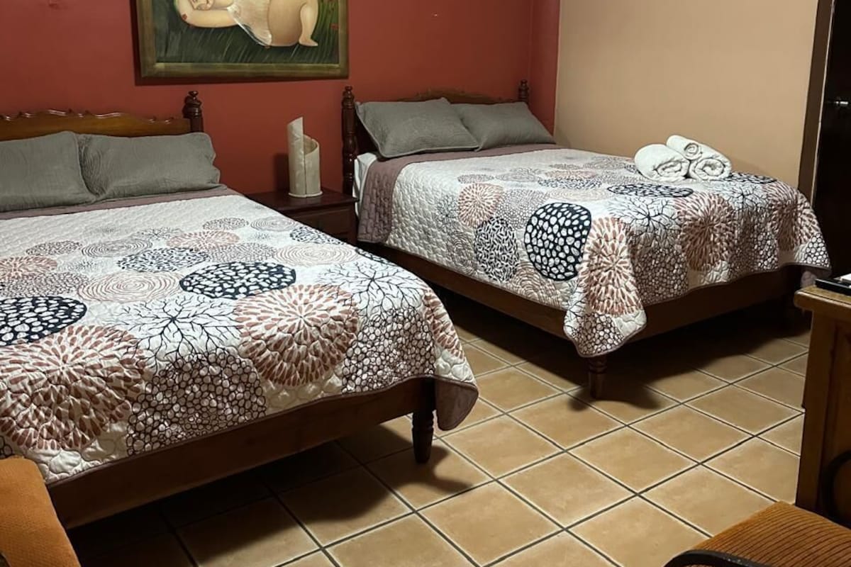 Un dormitorio con dos camas, un cuadro en la pared y una silla.