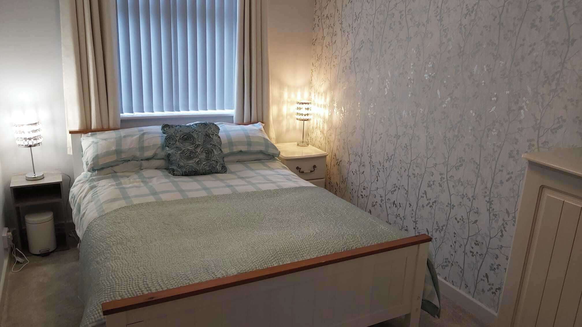 Un dormitorio con cama, mesitas de noche, lámpara y radiador.
