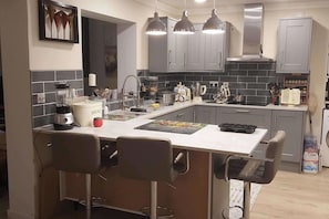 Uma cozinha moderna com ilha central, armários cinza e luminárias pendentes.