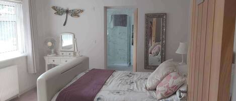 A bedroom with a bed, a dresser, a mirror, and a window.