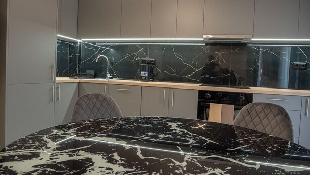 A modern kitchen with a marble countertop, a circular light fixture, and grey cabinetry. - Brand New Spacious 3BR Apartment (Athina)