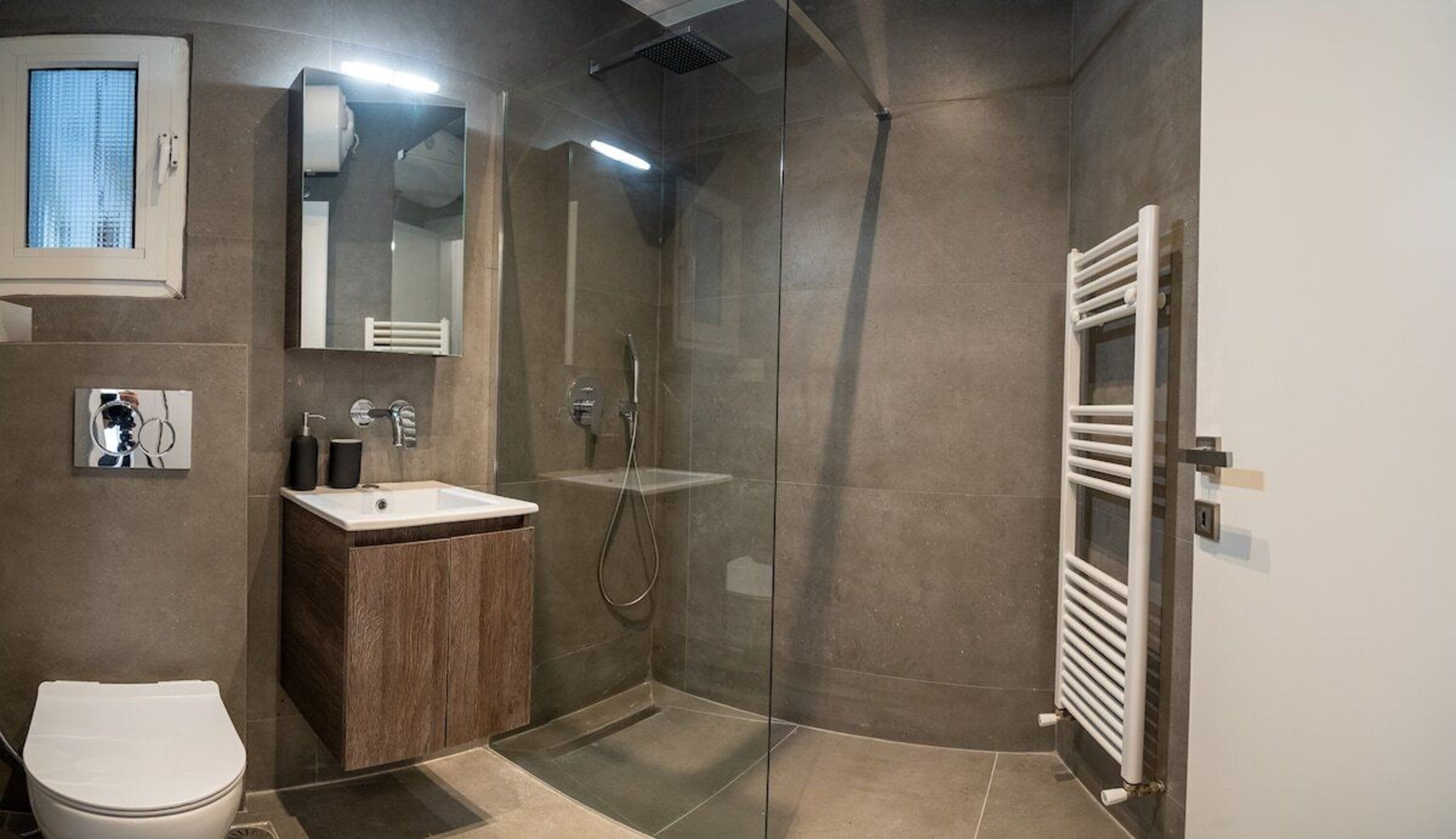 A modern bathroom with a glass shower enclosure, a white sink, and a toilet.