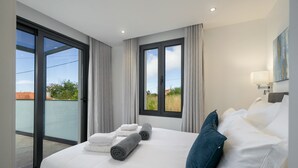 Quarto de hotel com uma cama grande, duas janelas, vista para o exterior e um quadro na parede.