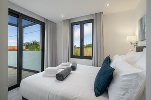 Ein Hotelzimmer mit einem großen Bett, zwei Fenstern, Blick ins Freie und einem Bild an der Wand.