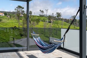 Eine Hängematte auf einem Balkon mit Blick auf eine grüne Landschaft.