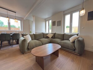 A modern living room with a sectional sofa, a wooden coffee table, and pendant lighting.