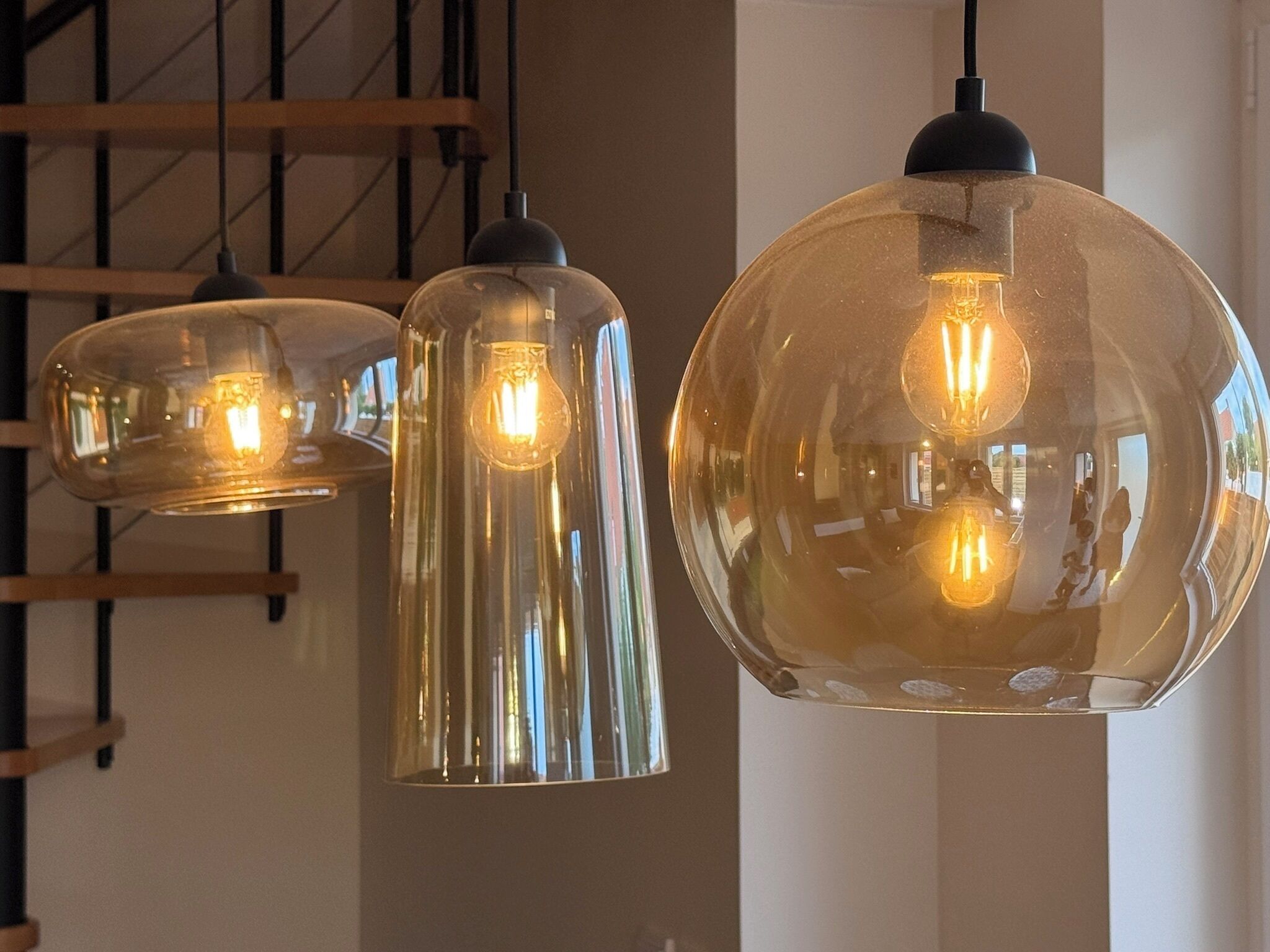 Drie hanglampen met een reflecterend oppervlak en zichtbare gloeilampen.