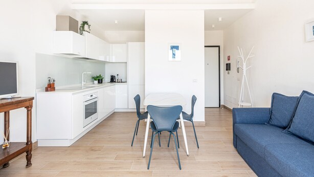 A modern kitchen with white cabinets, a dining area with blue chairs, and a blue sofa. - Igiea Florio Sea View by Wonderful Italy (Palermo)