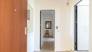 A hallway with a wooden door on the left, a white door on the right, and a mirror on the wall. - Igiea Florio Sea View by Wonderful Italy (Palermo)