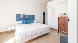 A bedroom with a bed, a nightstand, a dresser, and a mirror. - Igiea Florio Sea View by Wonderful Italy (Palermo)
