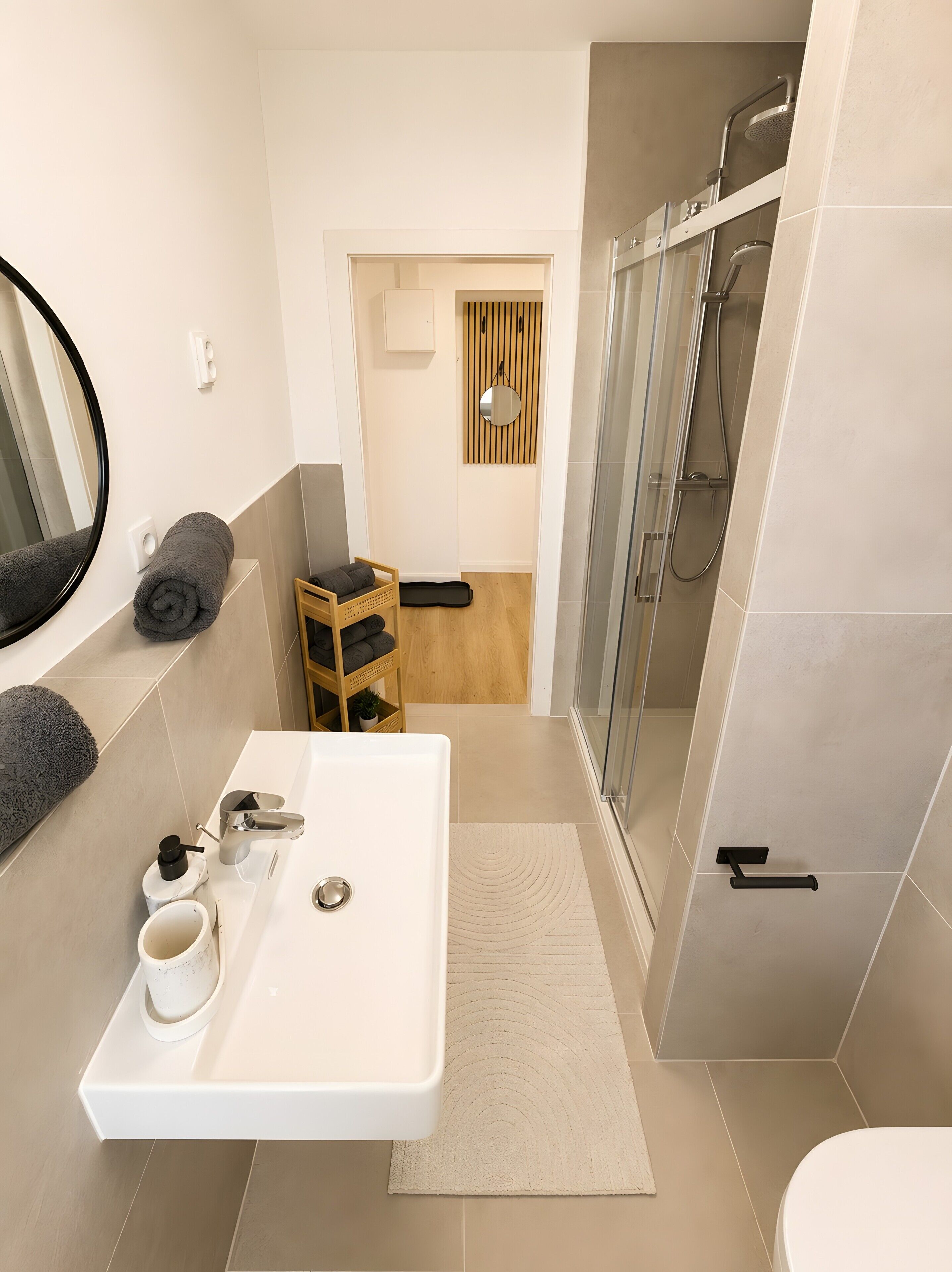 A modern bathroom with a white sink, mirror, and shower.