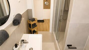 A modern bathroom with a white sink, mirror, and shower.